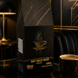 A 12oz bag of Art Deco Noir Medium Roasted Coffee sits on a polished black marble table next to a matching black coffee cup and saucer, set against a luxurious dark background with gold accents.
