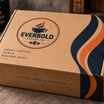 A kraft cardboard coffee subscription box from Everbold Coffee Co. with a printed logo and wavy navy, cream, and orange graphic accents on the side, photographed on a countertop with coffee beans and a mug in the background.