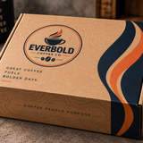 A kraft cardboard coffee subscription box from Everbold Coffee Co. with a printed logo and wavy navy, cream, and orange graphic accents on the side, photographed on a countertop with coffee beans and a mug in the background.