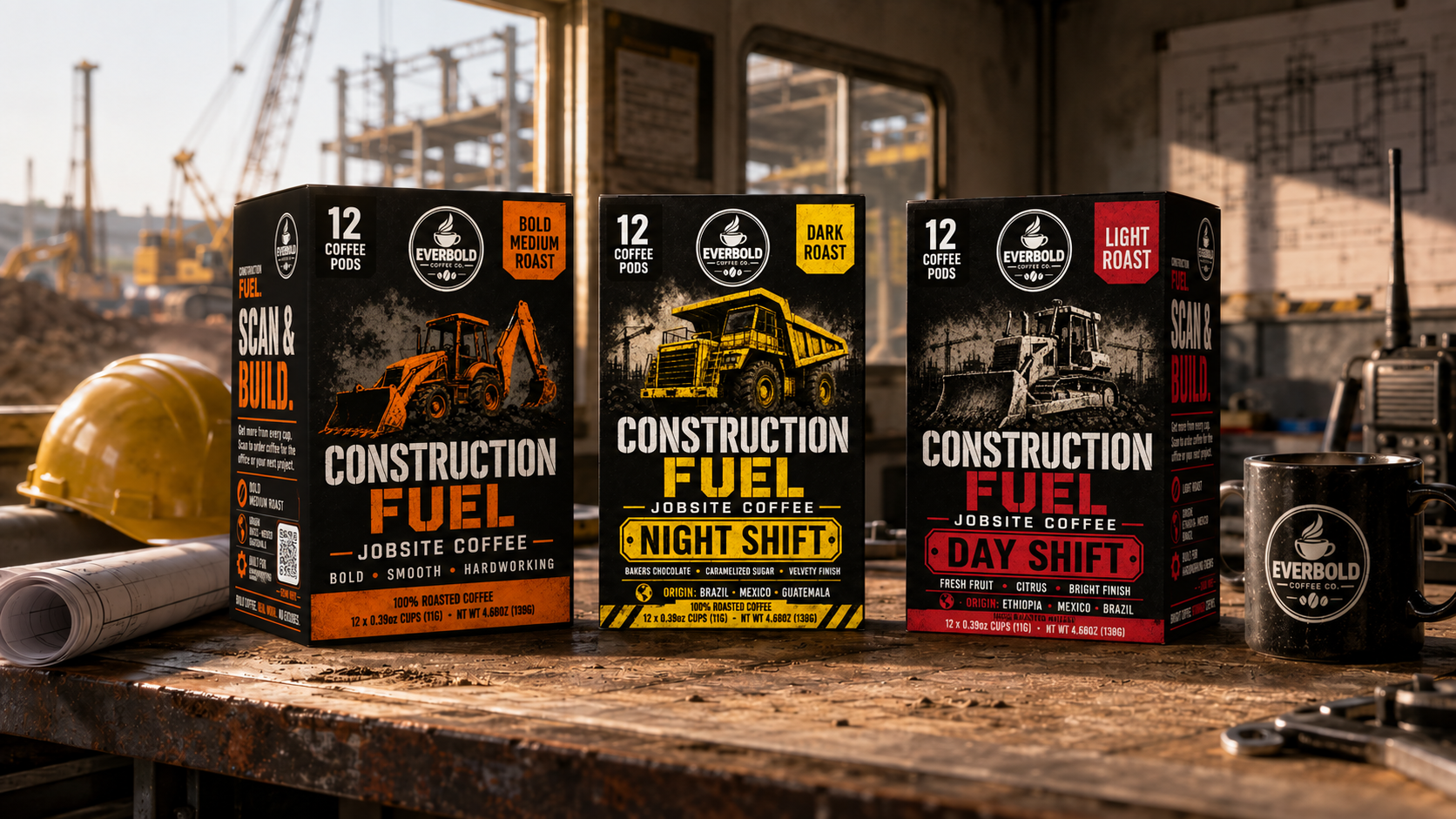 Three Everbold Construction Fuel coffee boxes displayed on a workbench in a construction site setting, alongside a yellow hard hat, rolled plans, and a black Everbold mug.